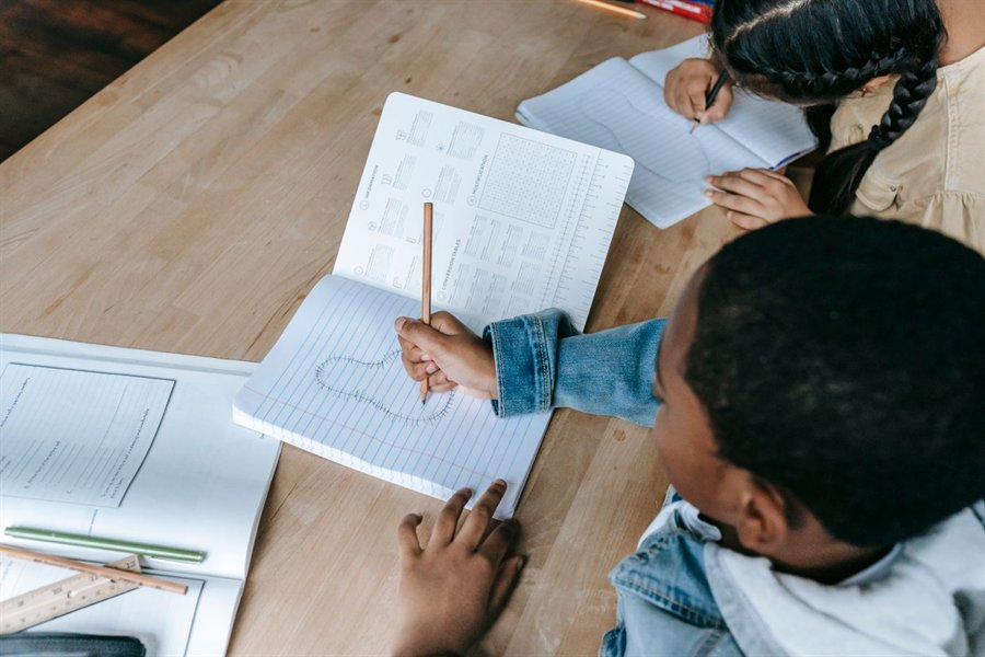 Students writing in notebooks at a desk